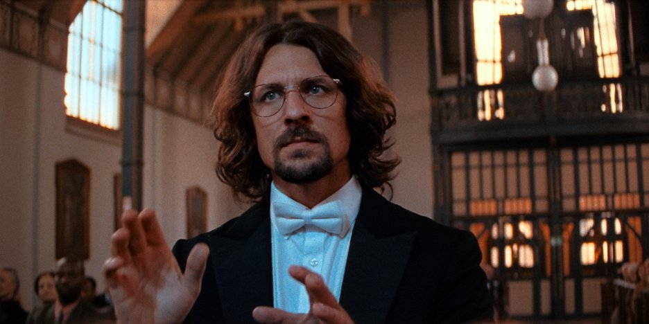 Still from Broken Voices — a choirmaster conducting in a grand hall